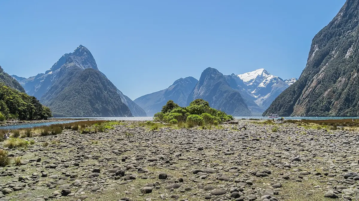 Fiorde de Milford Sound com o Mitre Peak refletido na água escura, cercado por montanhas